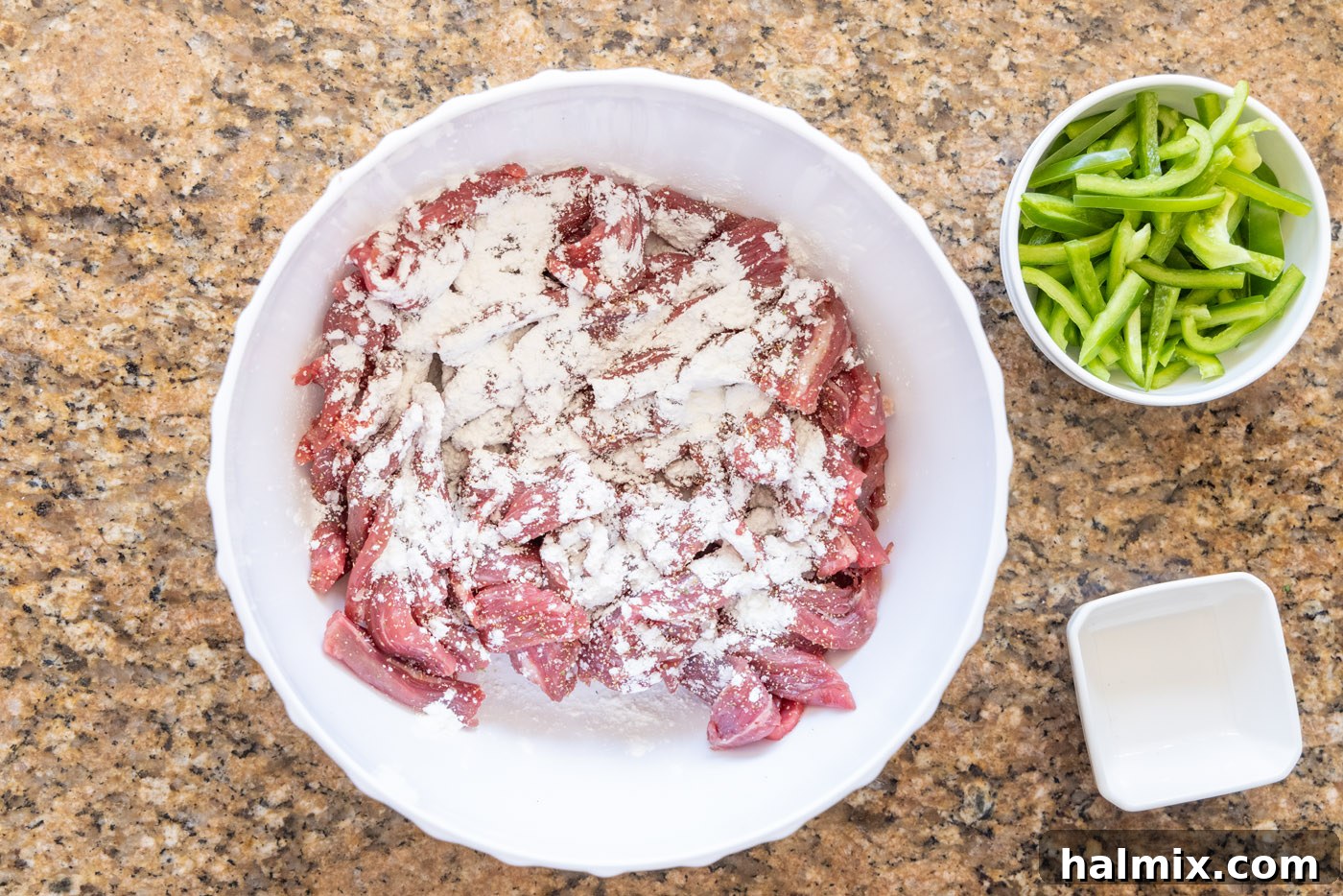 Thinly sliced flank steak being coated with cornstarch for velveting