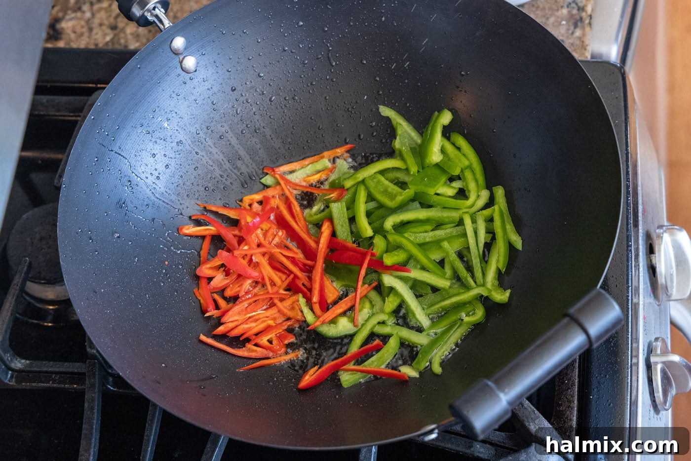 Red jalapenos and green peppers stir-frying in a hot wok