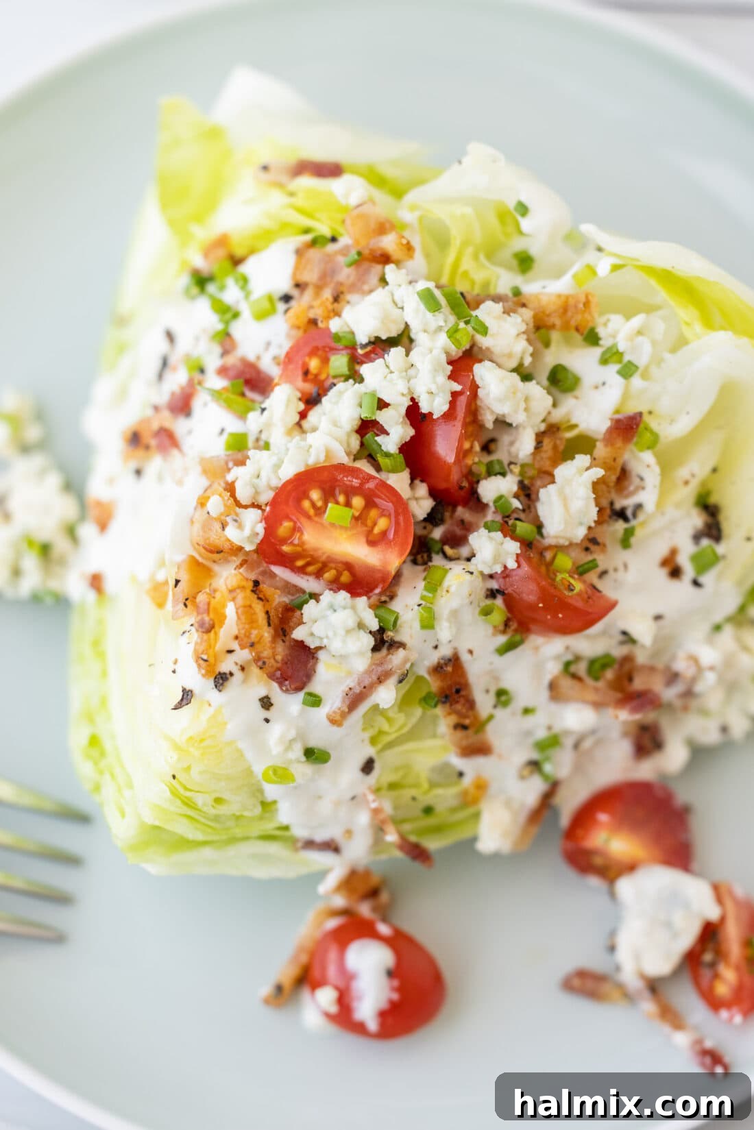 Close-up view of a Wedge Salad, highlighting the layers of toppings and creamy dressing.
