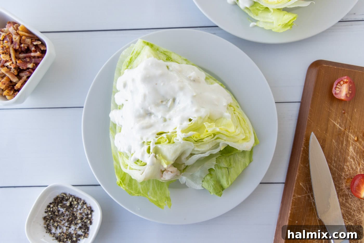 Bleu cheese dressing being drizzled on top of a wedge of iceberg lettuce.