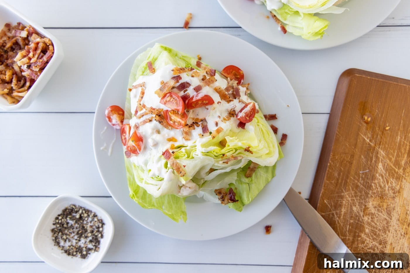 Cherry tomatoes, bacon, and bleu cheese dressing on iceberg lettuce wedge.