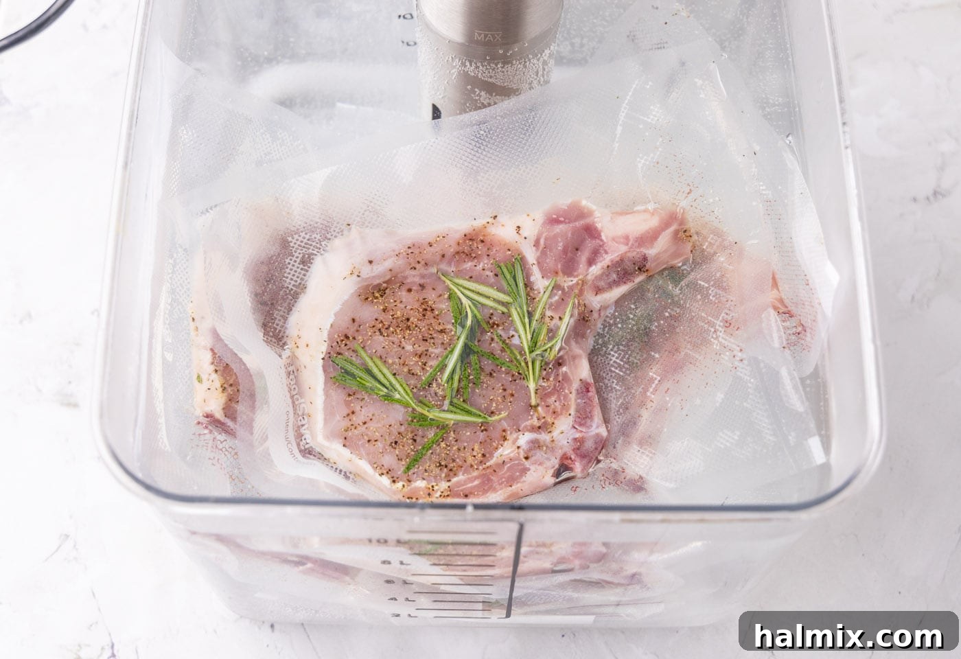 Close-up view of vacuum-sealed pork chops gently cooking in a sous vide bath.