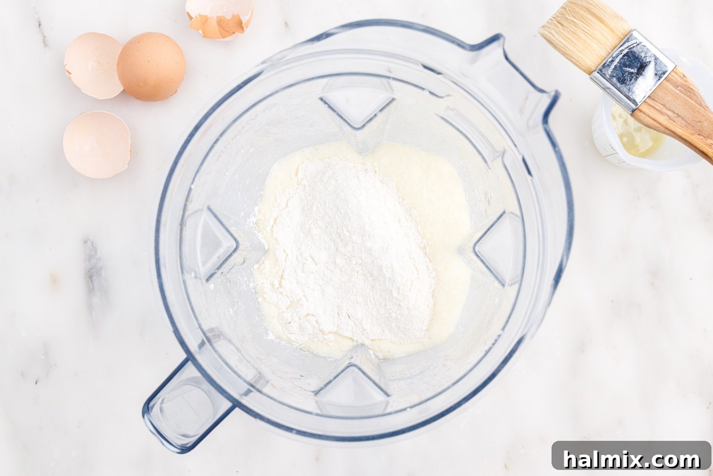 Golden Popovers 6 Adding all-purpose flour to the wet ingredients in a blender for popover batter.