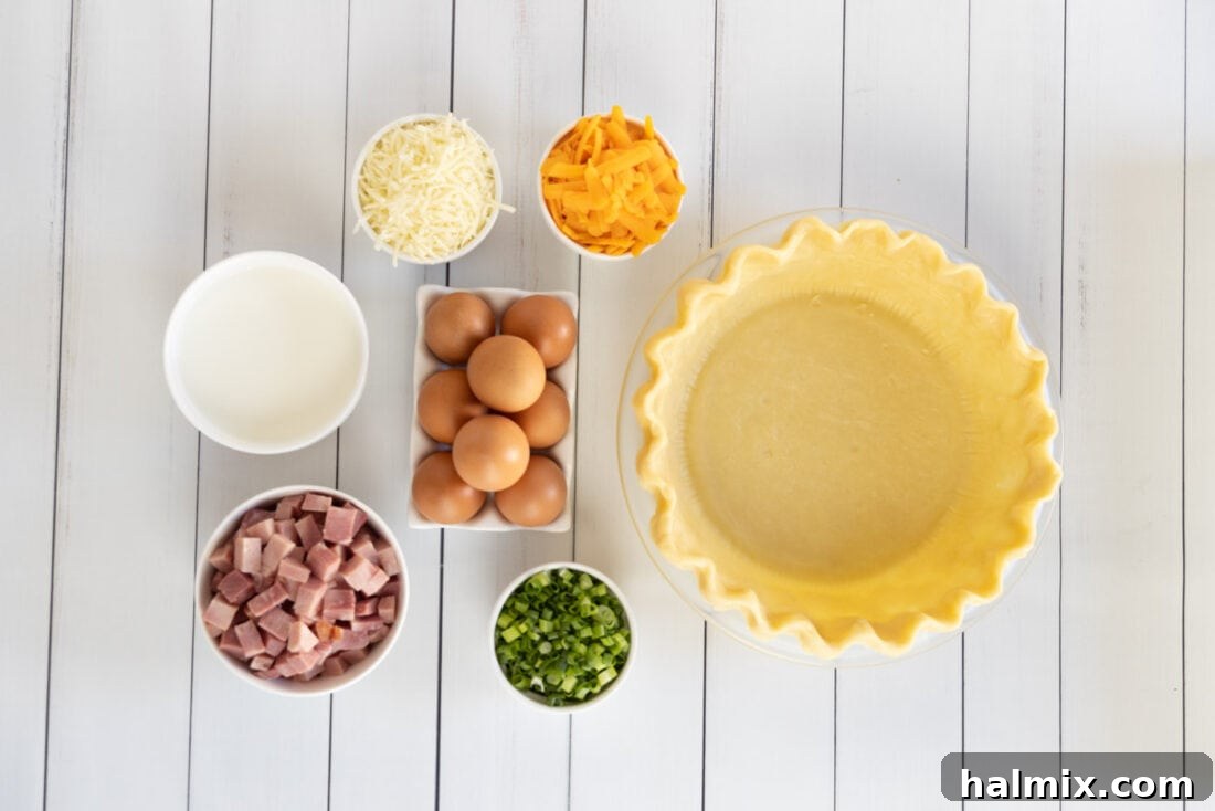 Assortment of fresh ingredients for quiche: eggs, milk, ham, cheeses, green onions, and pie crust.