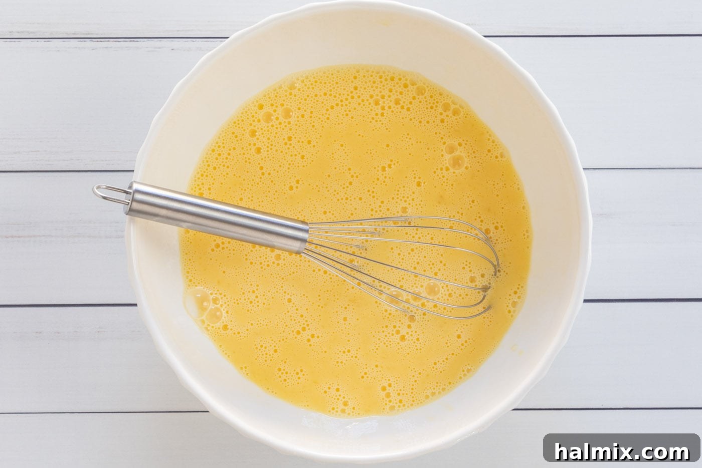 Egg and milk mixture being whisked in a bowl until smooth.