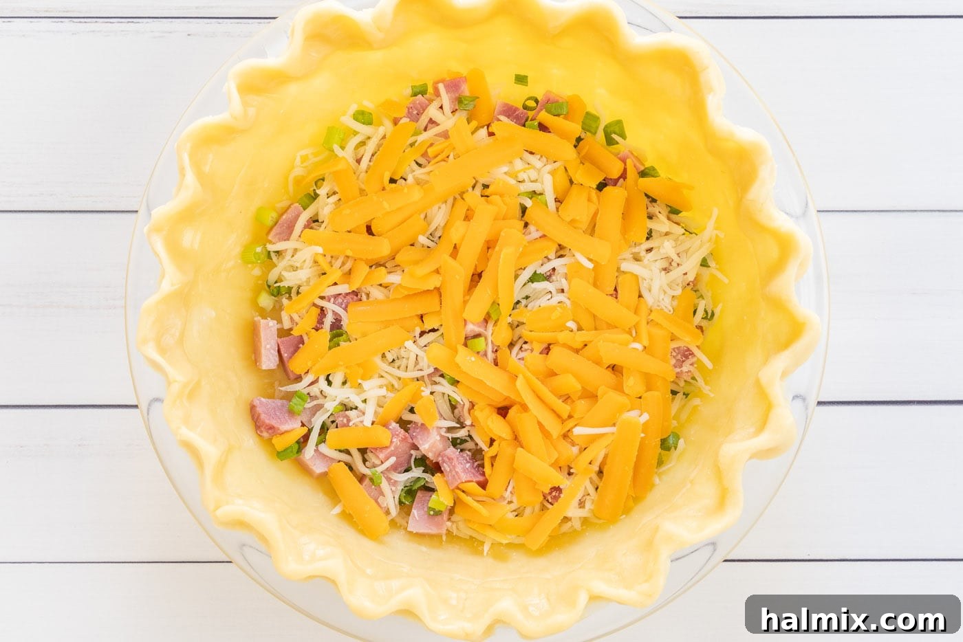 Cheddar cheese layered on top of mozzarella and ham in a pie crust.