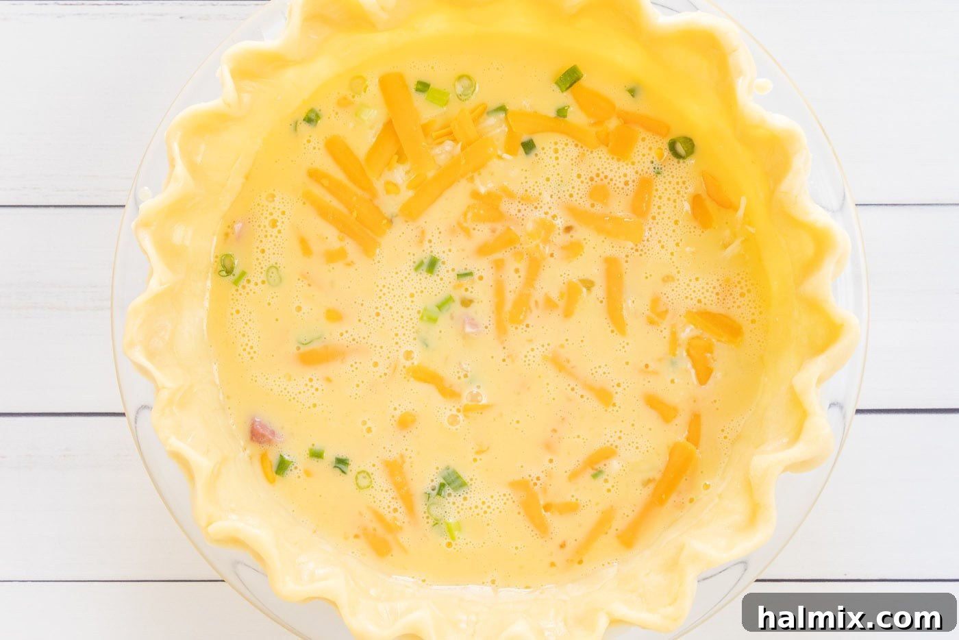 All initial quiche ingredients perfectly layered in the pie shell.