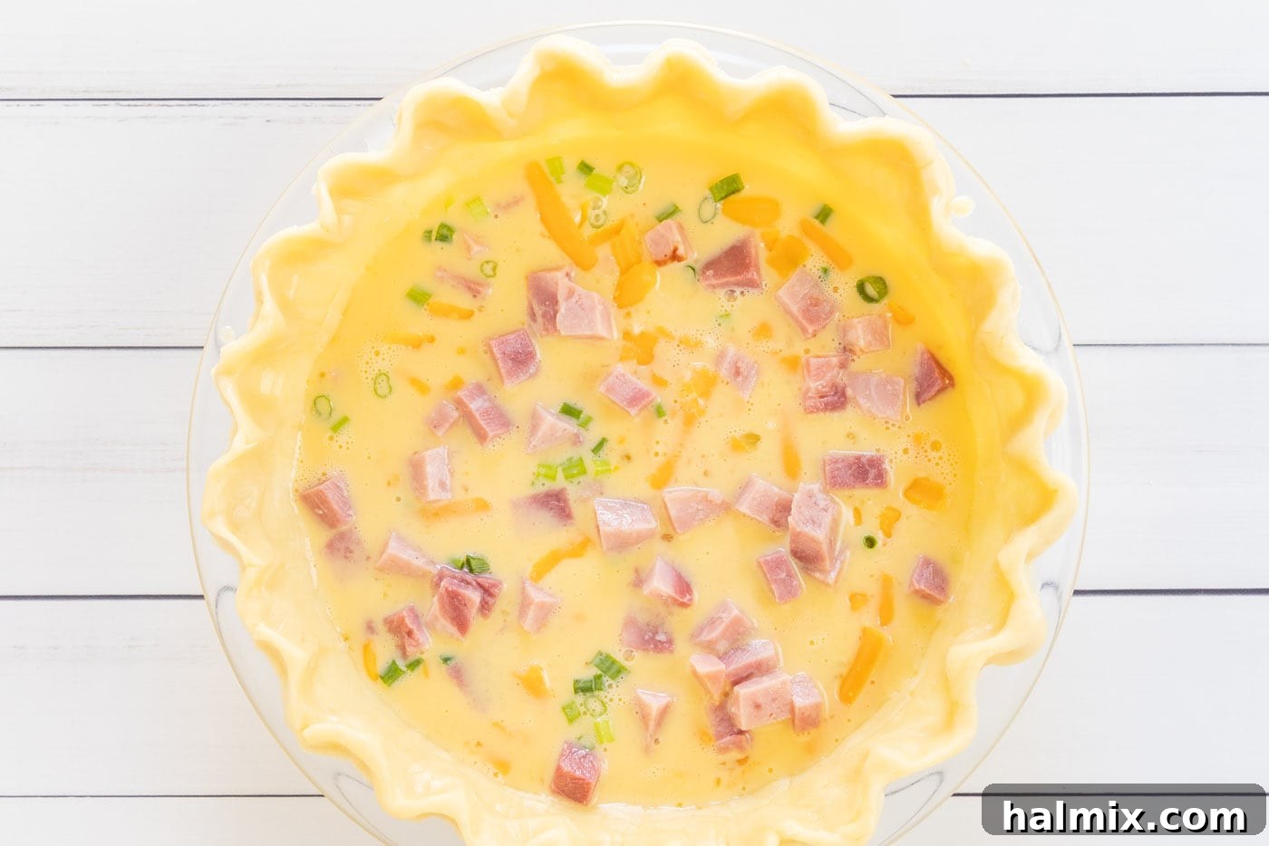 Homemade quiche mixture neatly arranged in a pie shell before baking.