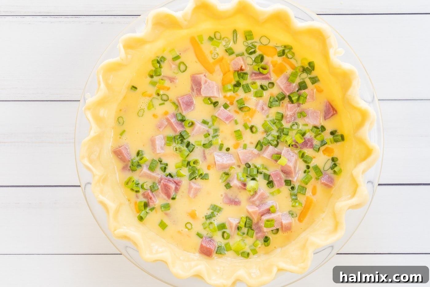 Fresh green onions as a top layer on the quiche mixture.