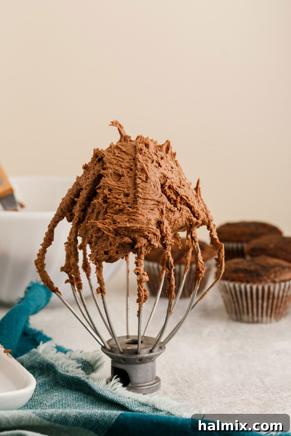 perfectly whipped chocolate buttercream frosting clinging to a mixer whisk attachment