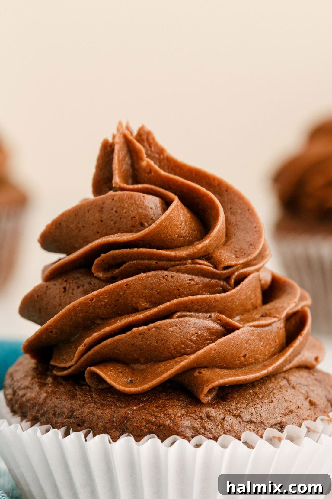 close-up view of a cupcake generously frosted with fluffy chocolate buttercream and chocolate shavings