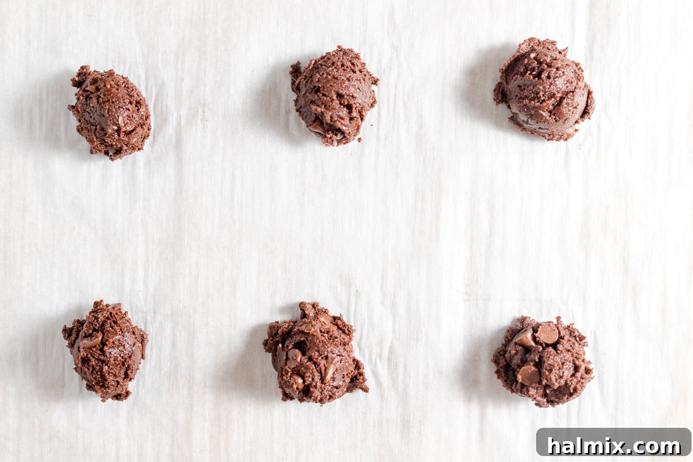 Luscious Chocolate Cake Mix Bites 11 Scooped chocolate cake mix cookie dough balls arranged on a parchment-lined baking sheet.