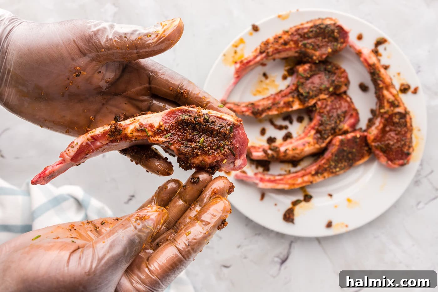 Hands massaging spice rub onto lamb chops