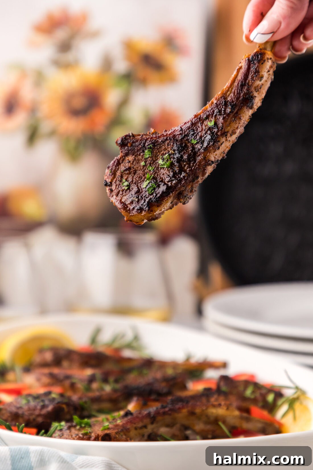 Hand holding a perfectly seared and baked lamb chop