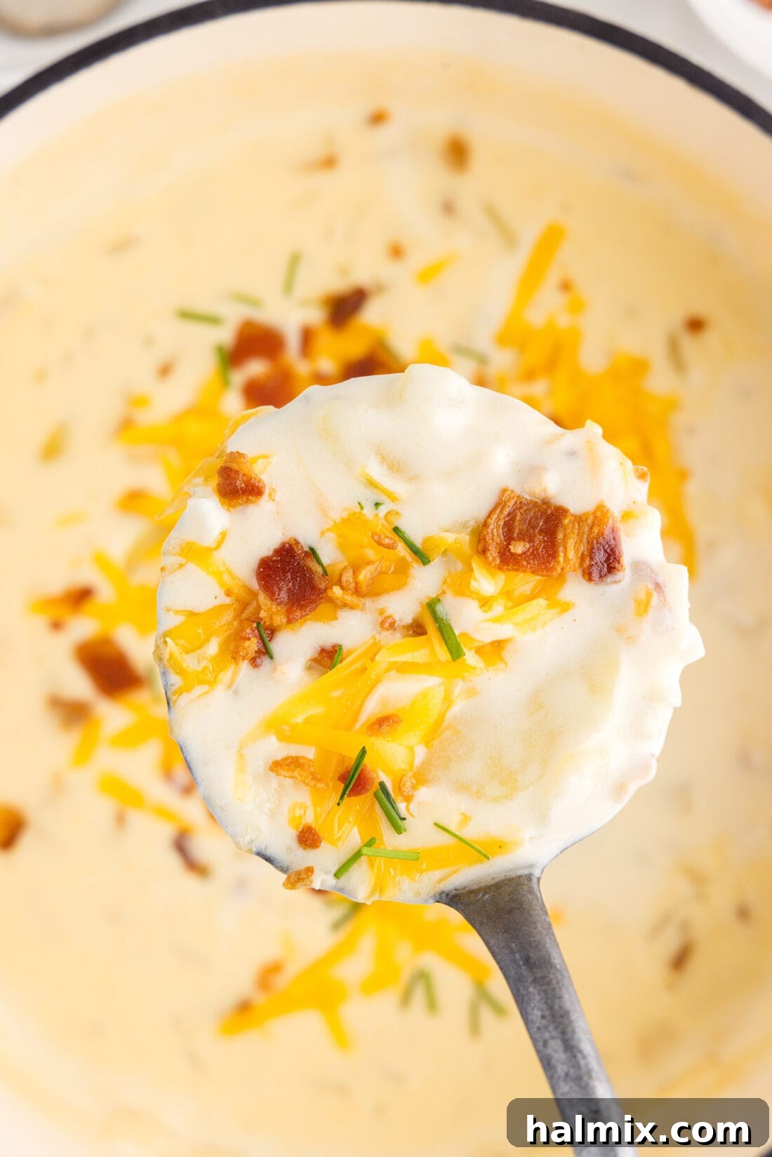 Hearty Loaded Baked Potato Soup 15 A ladle serving a generous portion of creamy Baked Potato Soup from a large pot, showing its rich texture and topping potential.