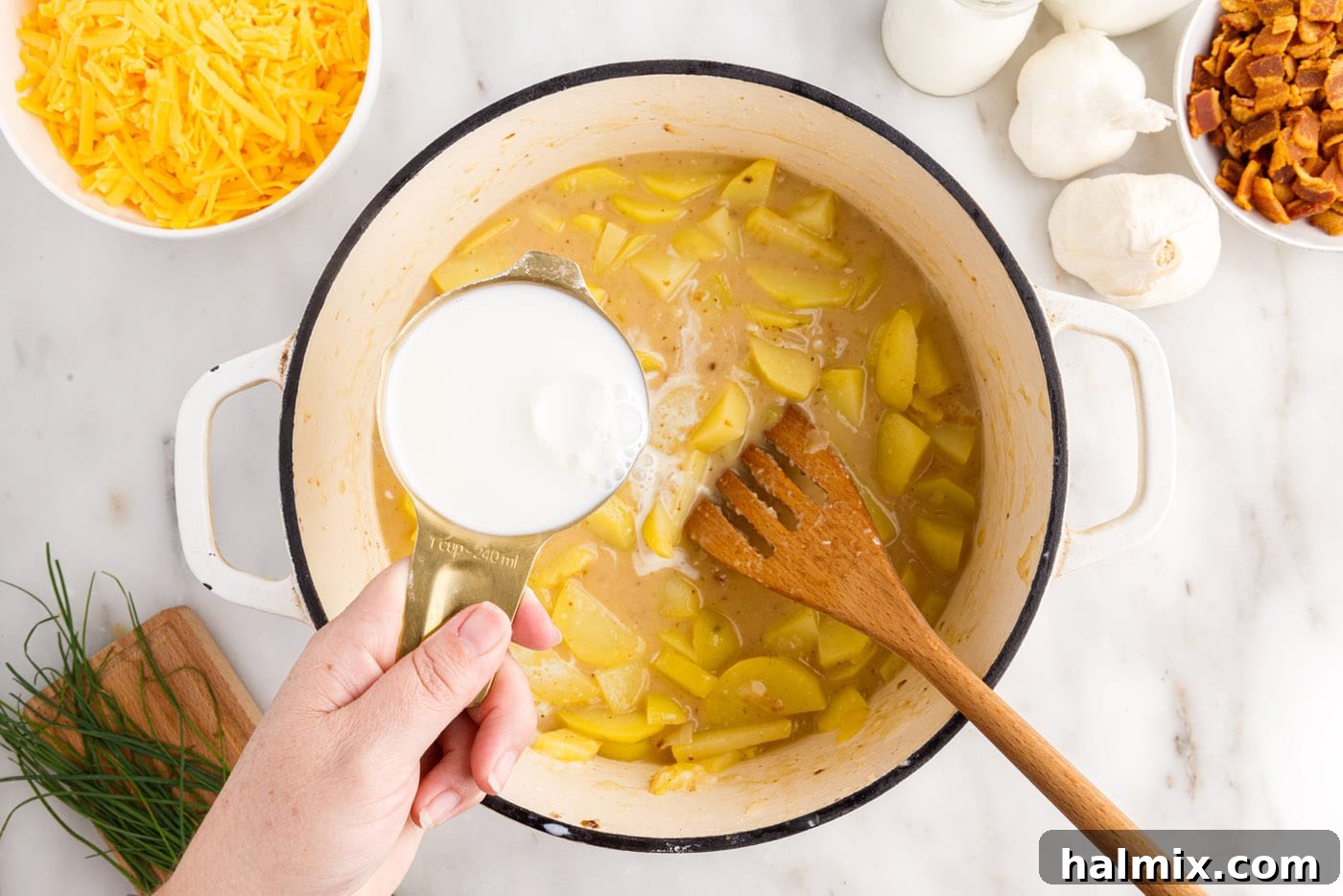 Hearty Loaded Baked Potato Soup 9 Adding milk to the simmering potato soup mixture in a stockpot.