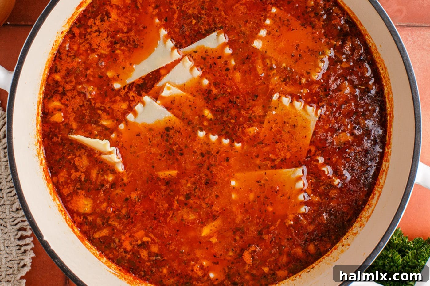 Cut lasagna noodles being added to the simmering lasagna soup pot