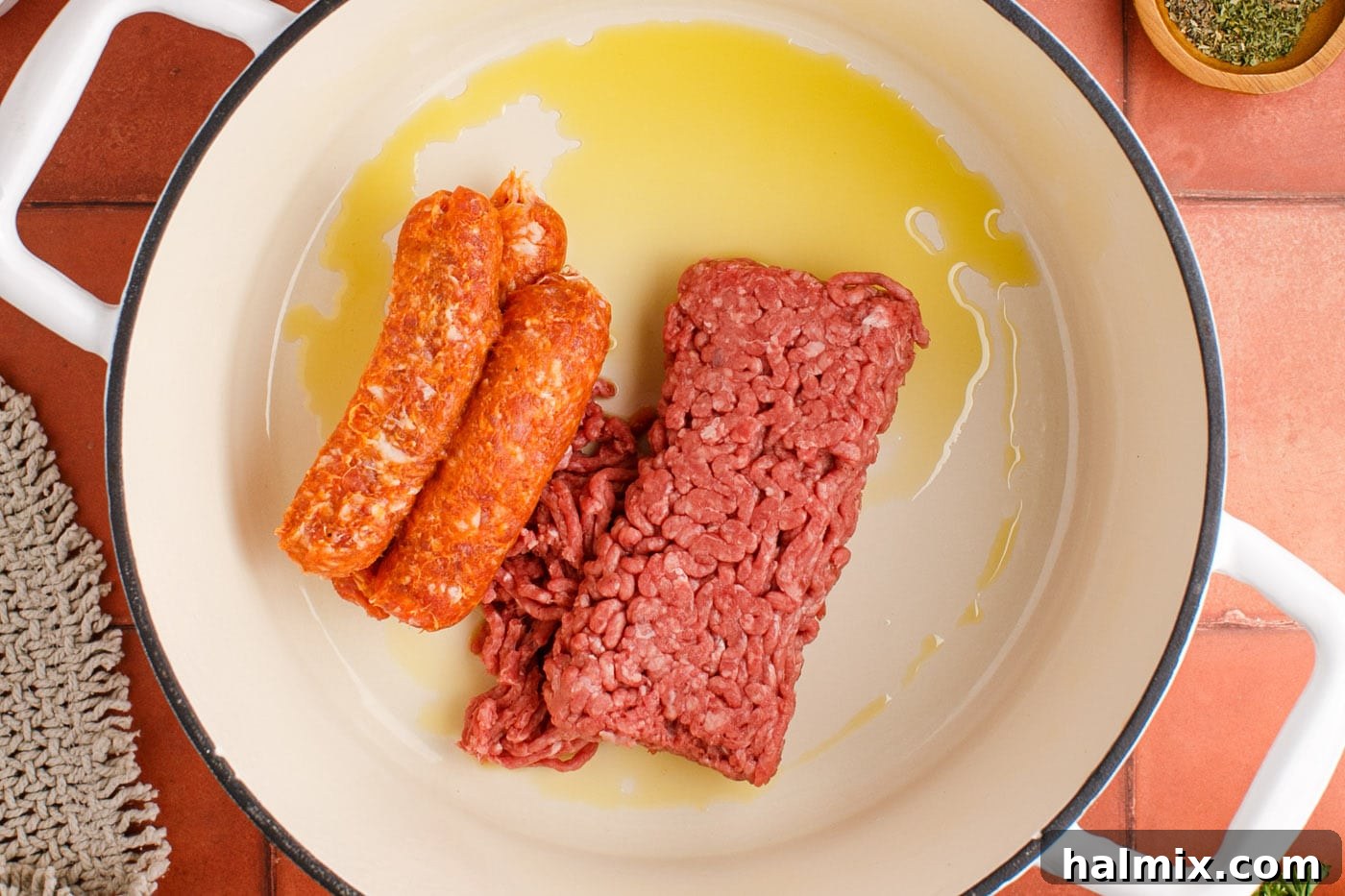 Ground Italian sausage and lean ground beef browning in a large soup pot with olive oil