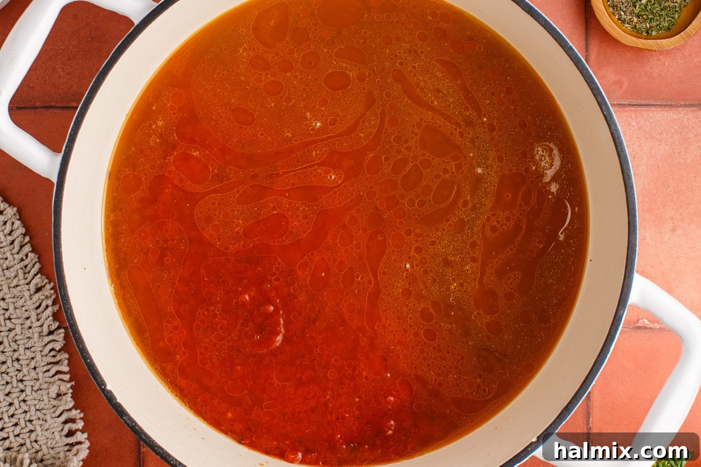 Marinara sauce being added to the browned ground beef and Italian sausage mixture in the pot