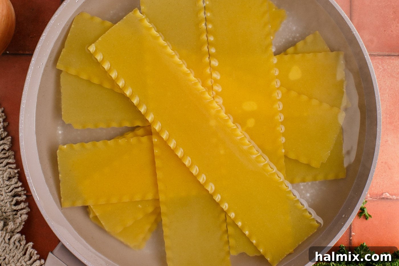 Lasagna noodles soaking in water in a pot to soften before cutting