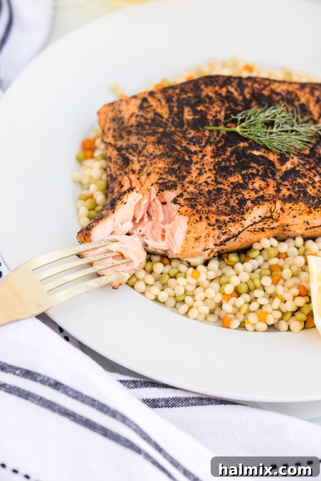 Silky Sous Vide Salmon 2 Sous Vide Salmon on a plate with a piece of salmon taken off and on a fork, showcasing its flakey texture