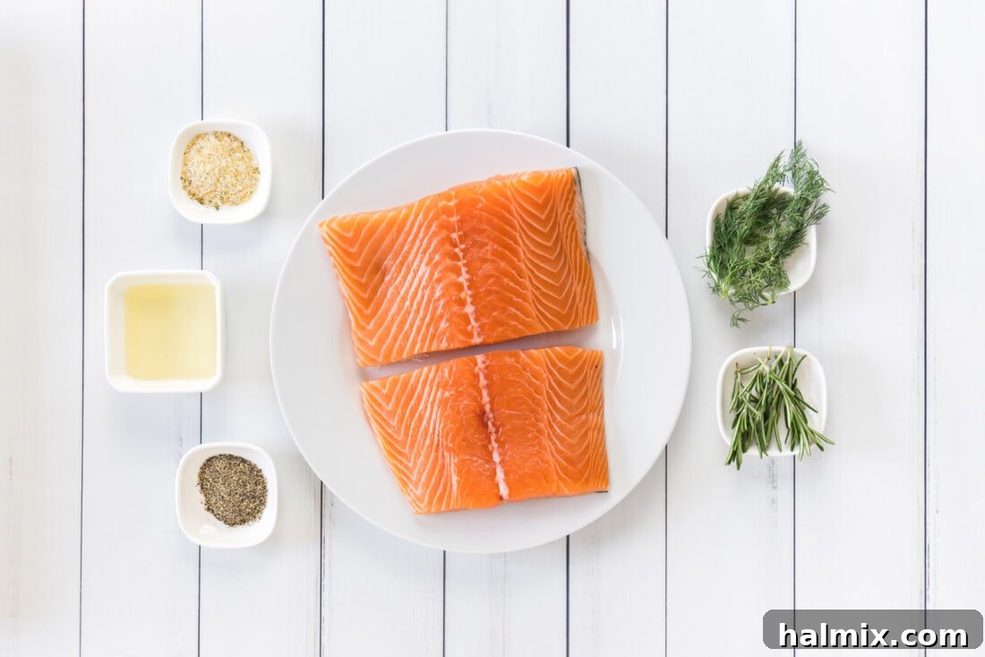 Silky Sous Vide Salmon 4 Ingredients for Sous Vide Salmon laid out on a cutting board, including fresh salmon, olive oil, garlic salt, pepper, and fresh herbs.