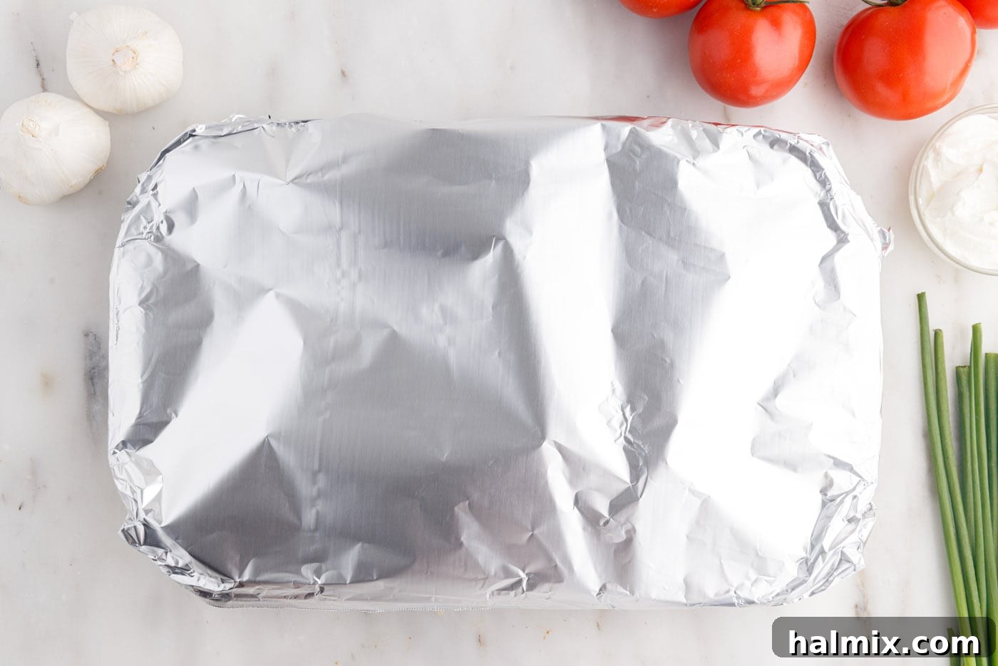 Aluminum foil covering the Mexican lasagna in the casserole dish, ready for baking to perfection