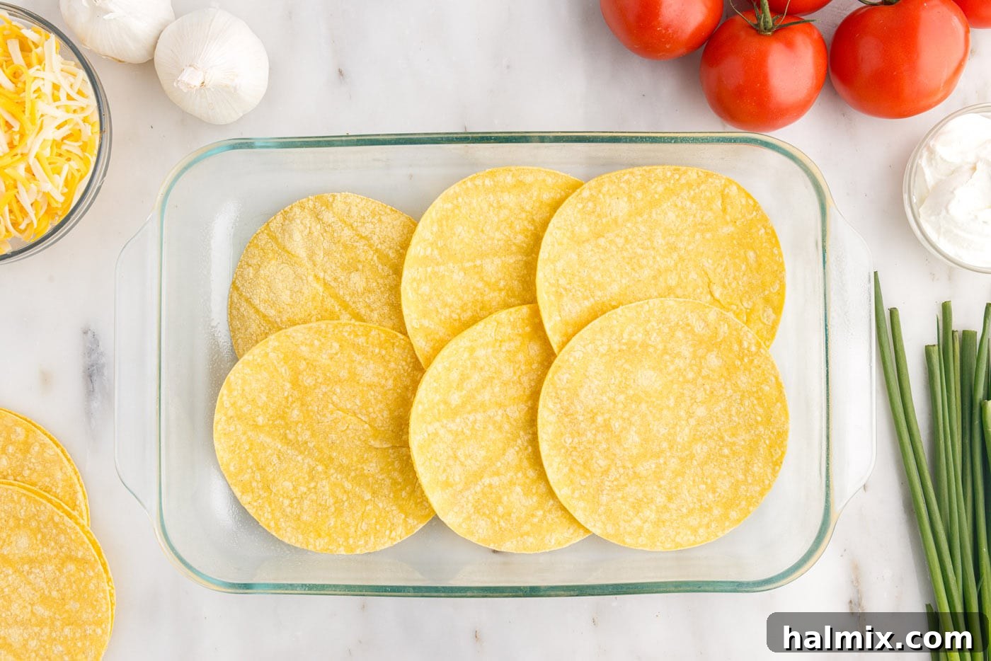Corn tortillas meticulously laid out as the first layer in a baking dish, forming a sturdy base