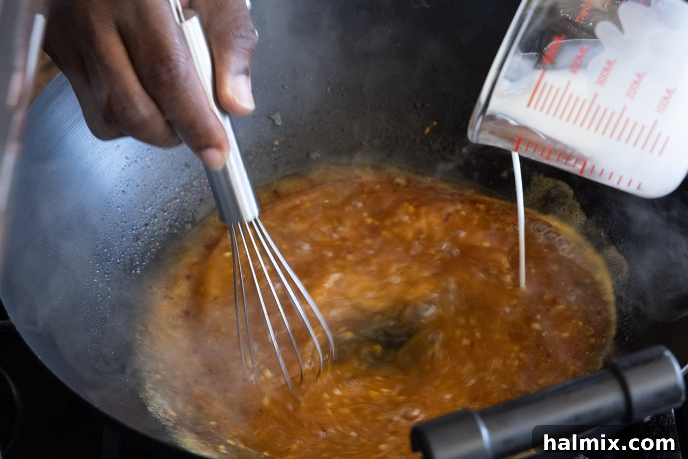 whisking cornstarch slurry into sauce in a skillet