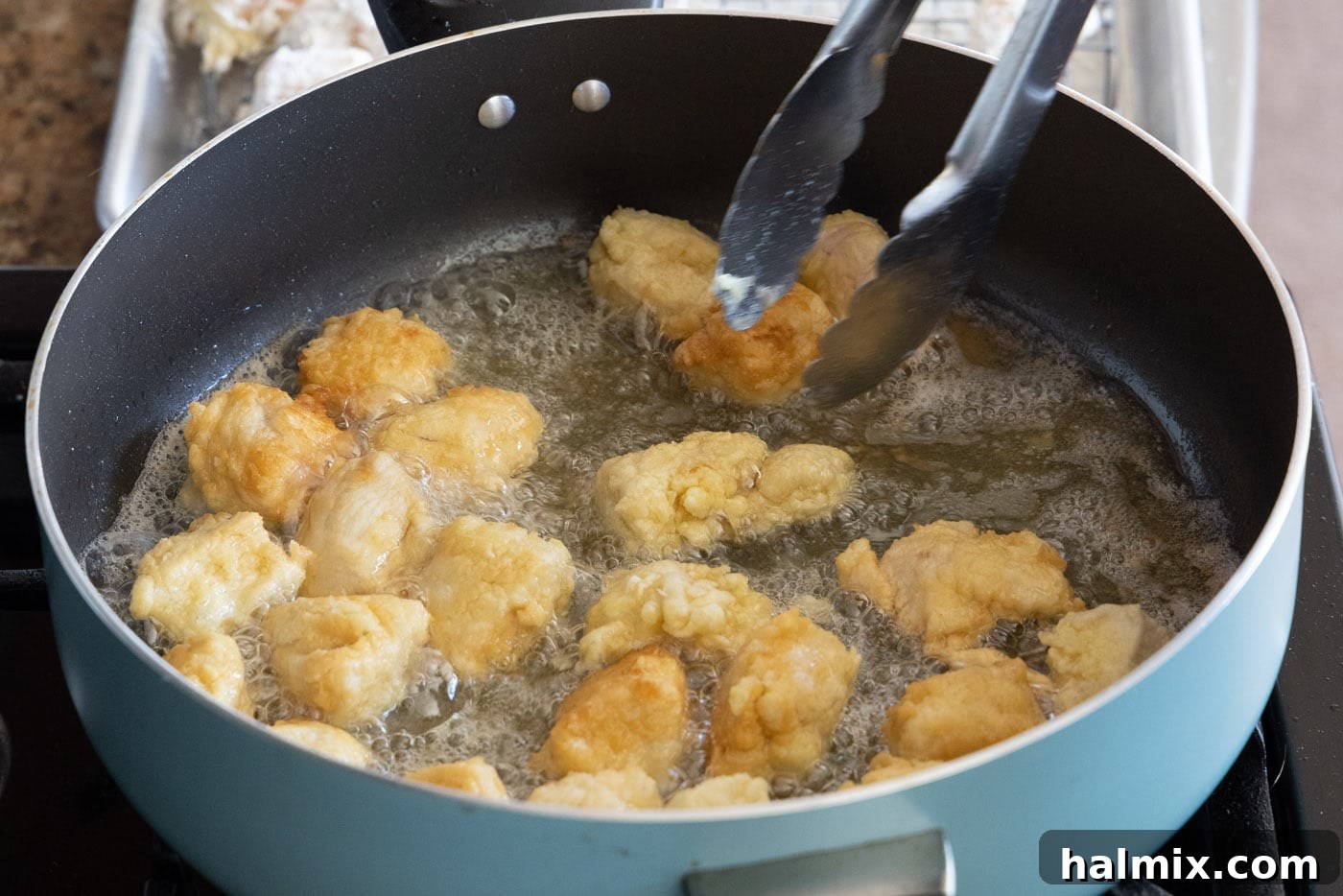 flipping chicken in a skillet of oil