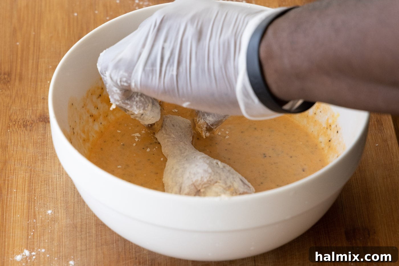 dipping chicken legs in spiced egg mixture