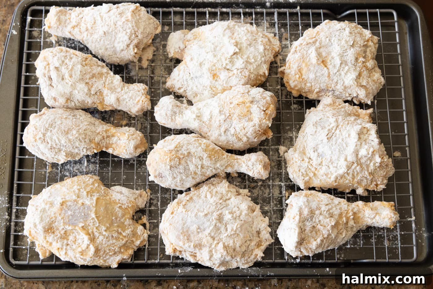 flour and egg dredged chicken thighs and legs on a baking sheet