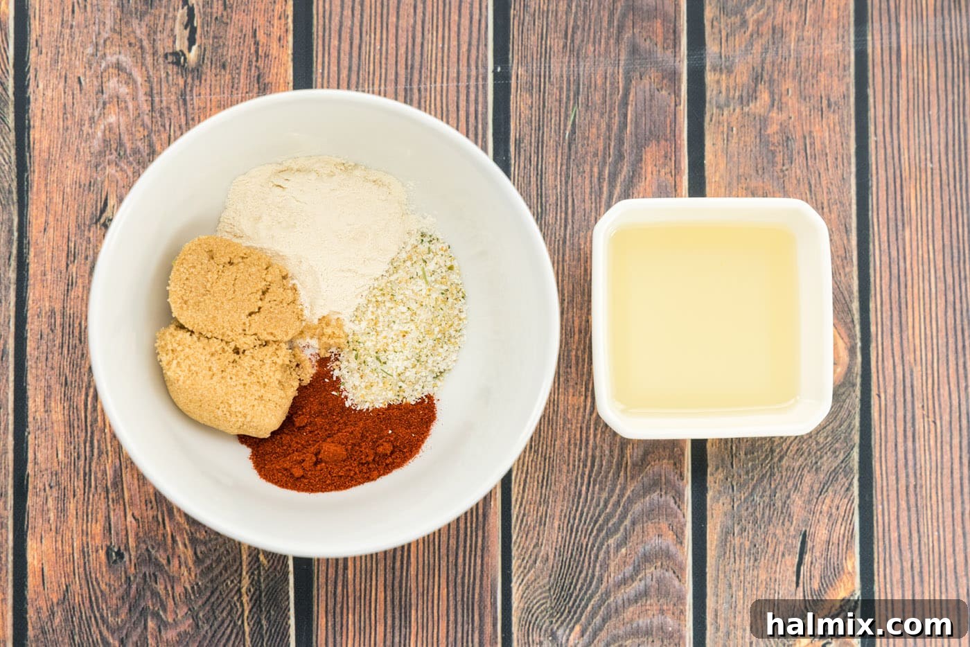 seasonings in a bowl next to olive oil, mixed to form a paste