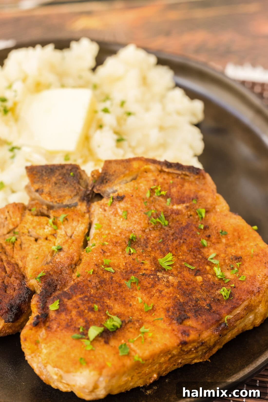 Tender Instant Pot Pork Chops 9 Close up of a tender Instant Pot Pork Chop on a plate, showing its juicy interior and crispy crust.