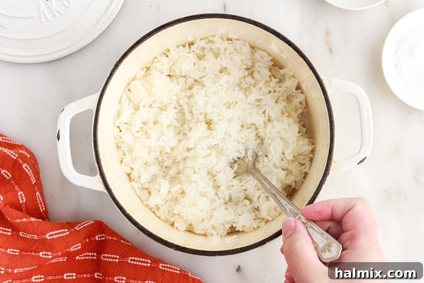 Fluffing perfectly cooked white rice with a fork in a saucepan