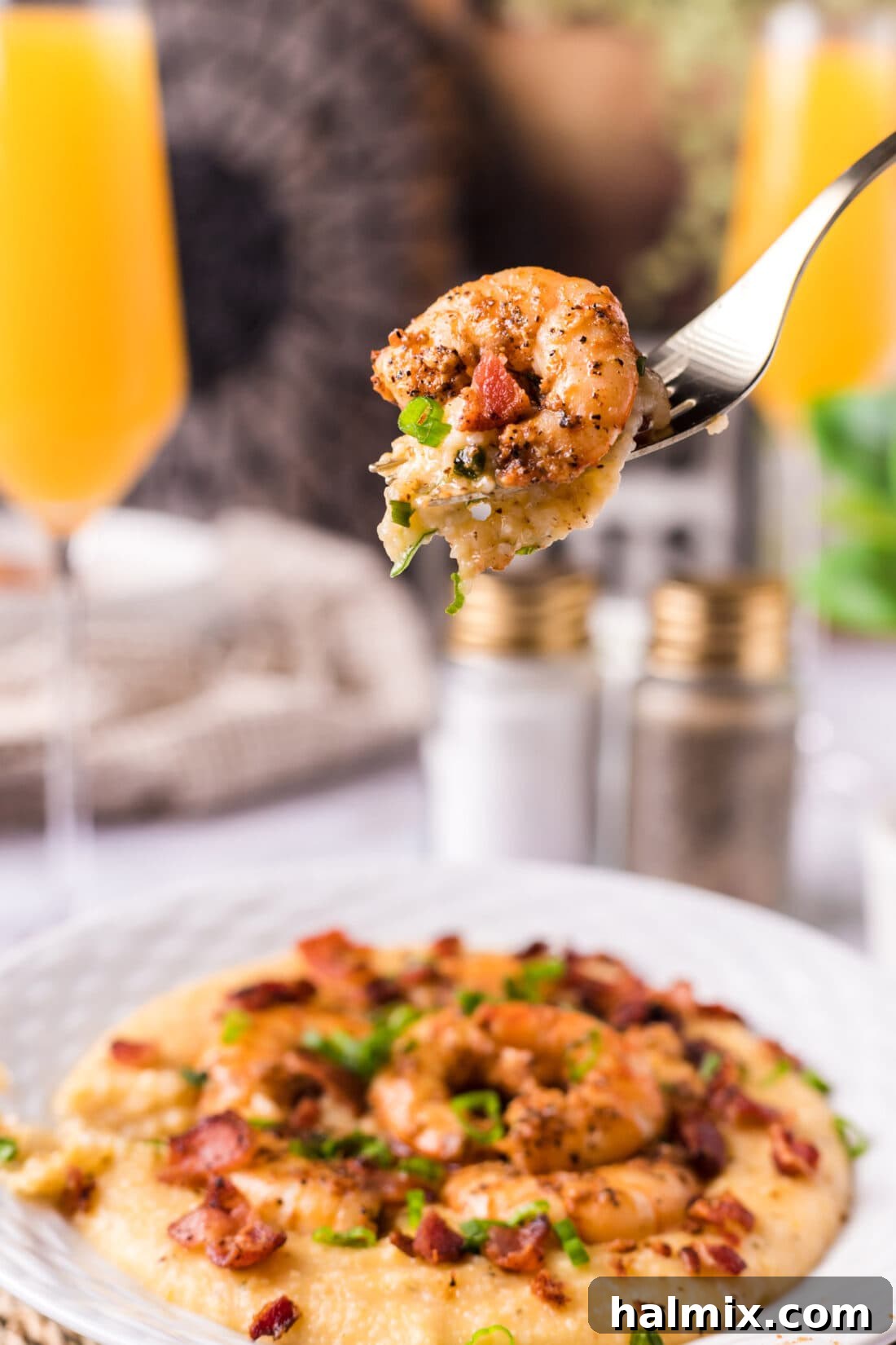 A fork lifting a delicious bite of cheesy shrimp and grits, showcasing the perfectly cooked shrimp and creamy texture.