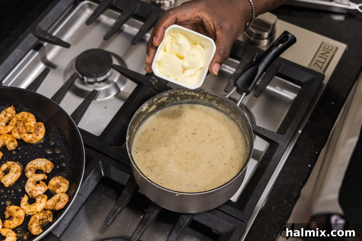 Adding a knob of butter to the hot, cooked grits in a saucepan, ready to be stirred in for richness.