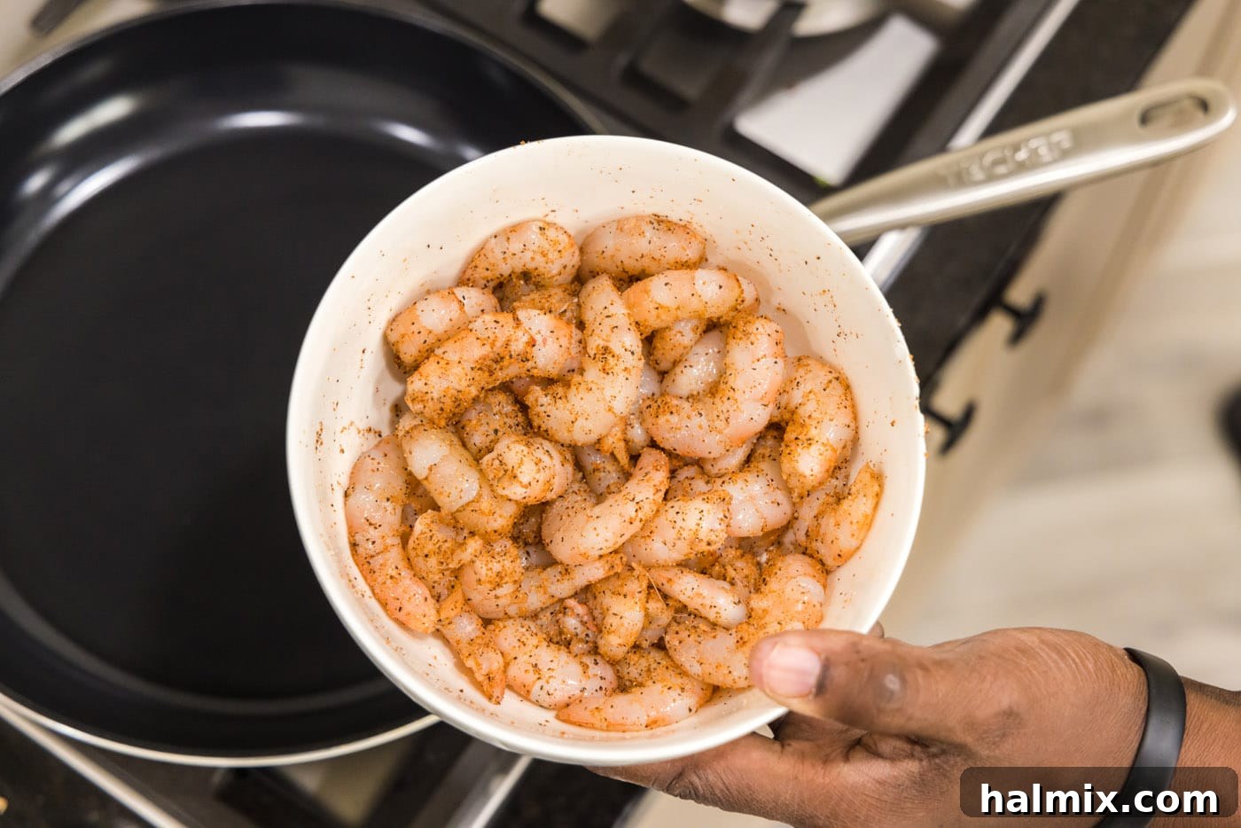 Raw shrimp seasoned generously with vibrant Cajun spices in a mixing bowl, ready for cooking.