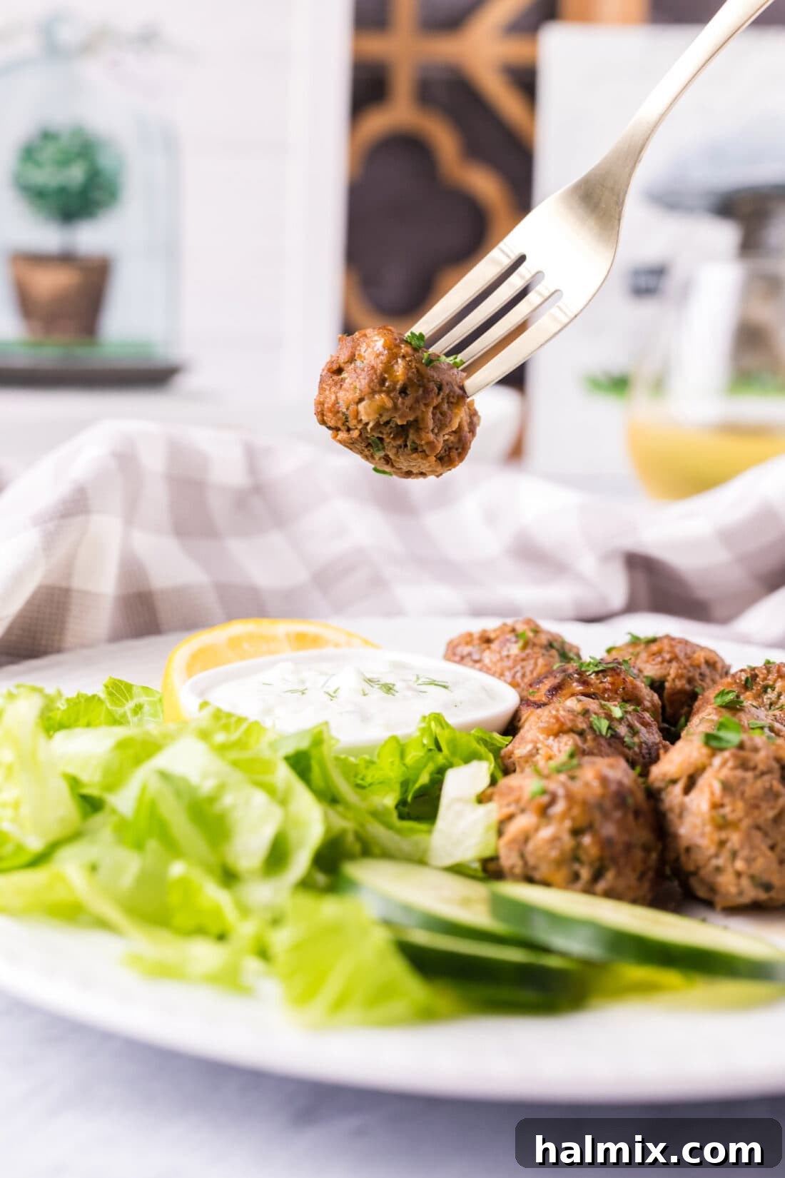 A single lamb meatball delicately placed on a fork, showcasing its tender texture and perfectly browned exterior.