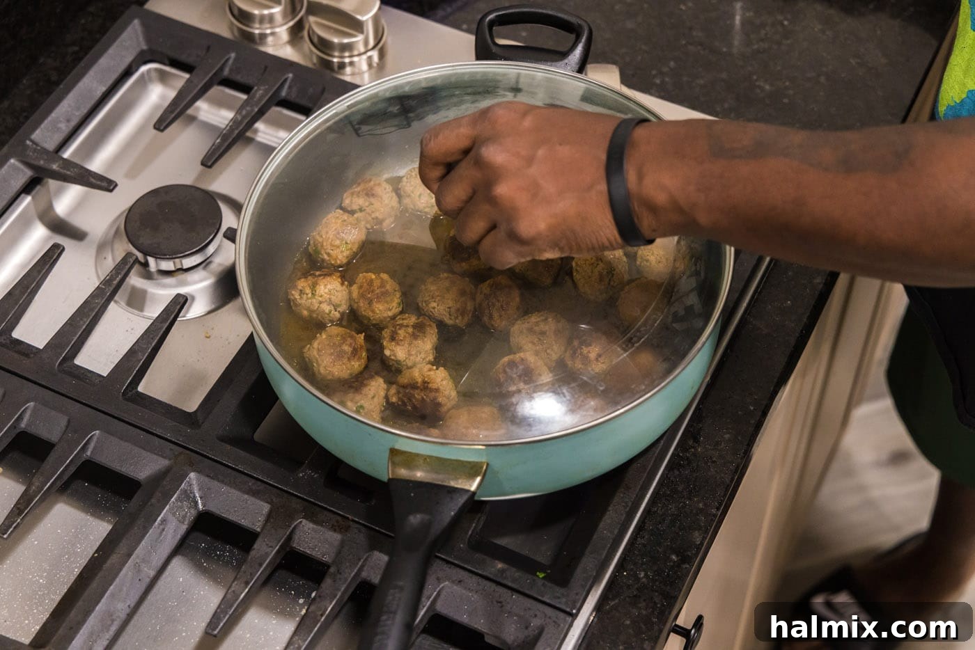 Skillet with lamb meatballs covered with a tight-fitting lid, allowing them to steam gently to finish cooking.