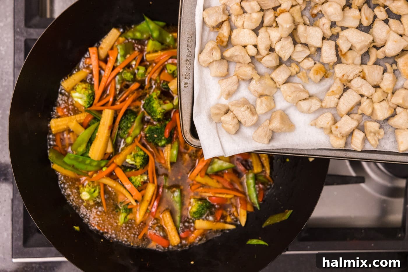 adding chicken back to wok with vegetables and sauce