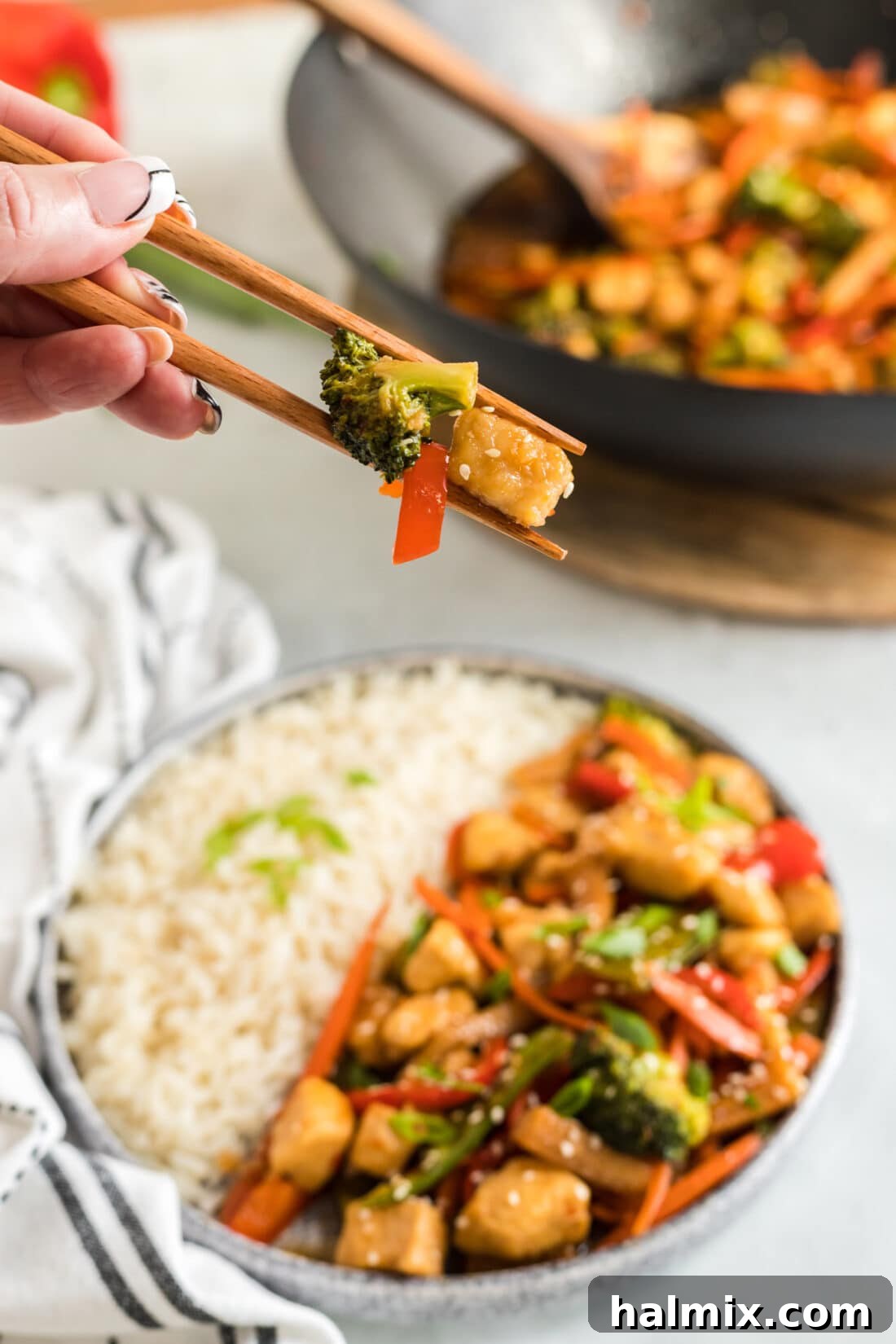 Pieces of Hunan Chicken held in chopsticks 