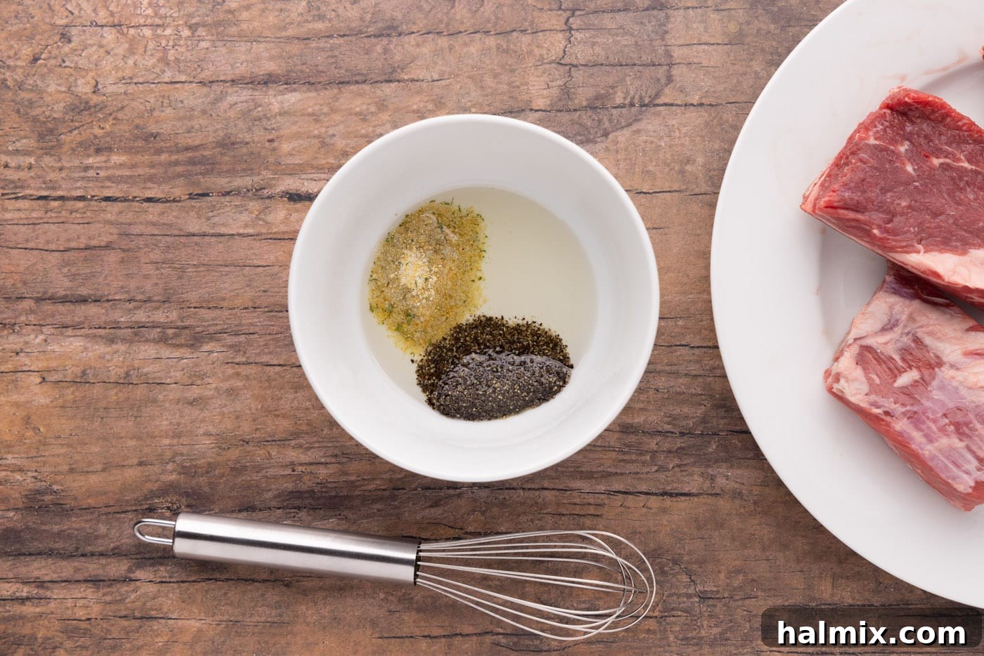 Fall-Off-The-Bone Beef Ribs 5 Olive oil, garlic salt, and black pepper being whisked together in a small white bowl.