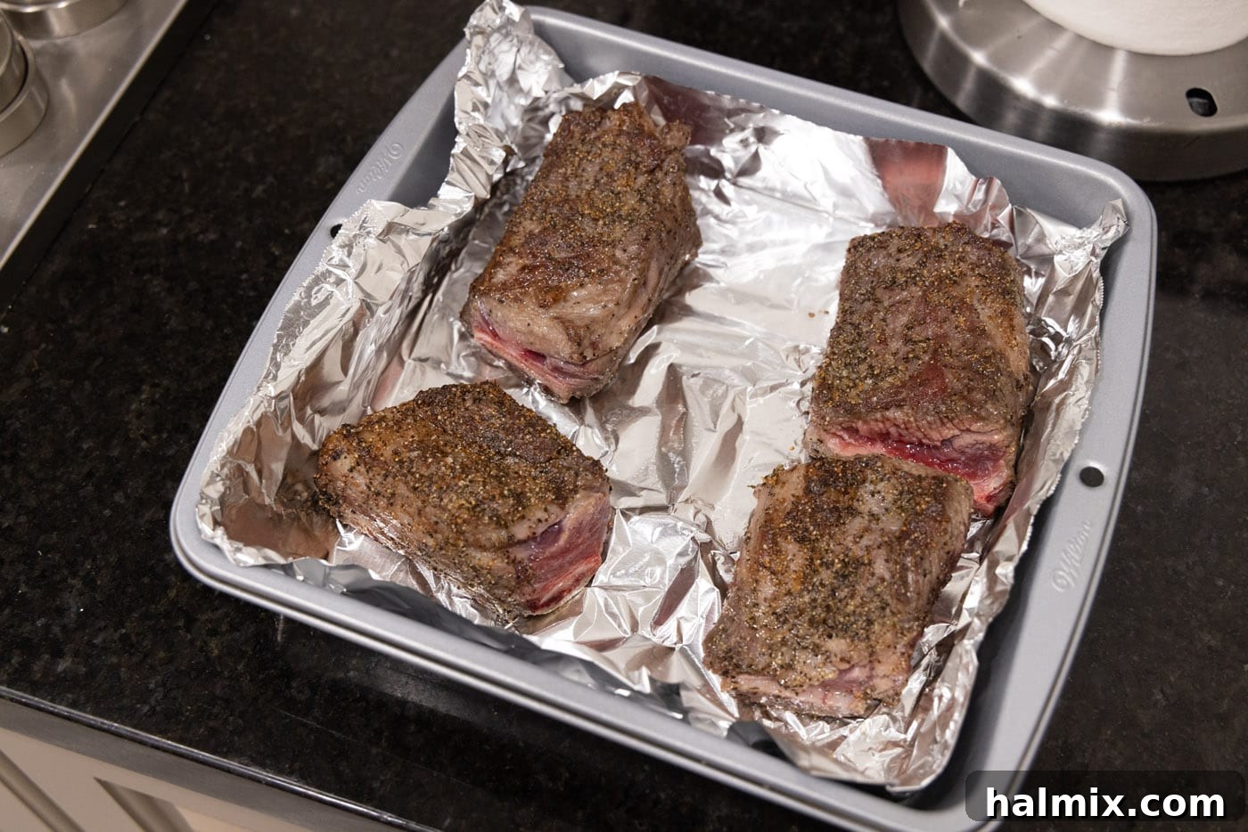 Fall-Off-The-Bone Beef Ribs 9 Seared short ribs arranged neatly in a foil-lined baking dish, ready for the oven.