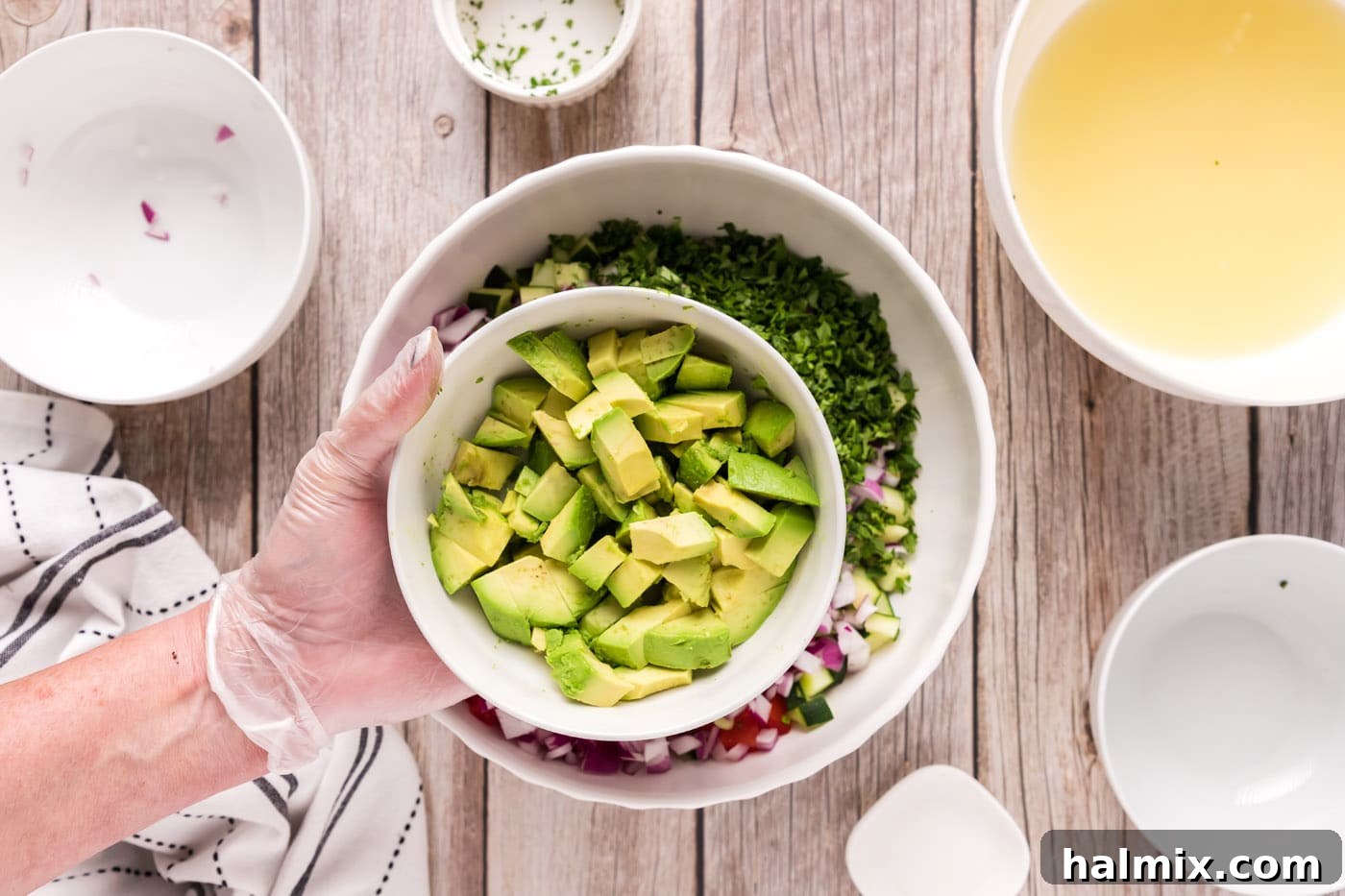 Zesty Shrimp Ceviche 12 adding avocado to bowl of diced fruits and vegetables with shrimp