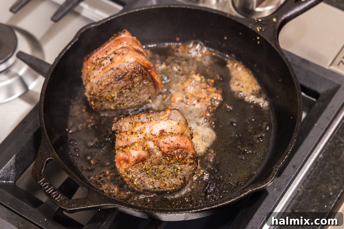 A perfectly seared bacon-wrapped filet mignon steak, with crispy bacon, cooking in a hot skillet.