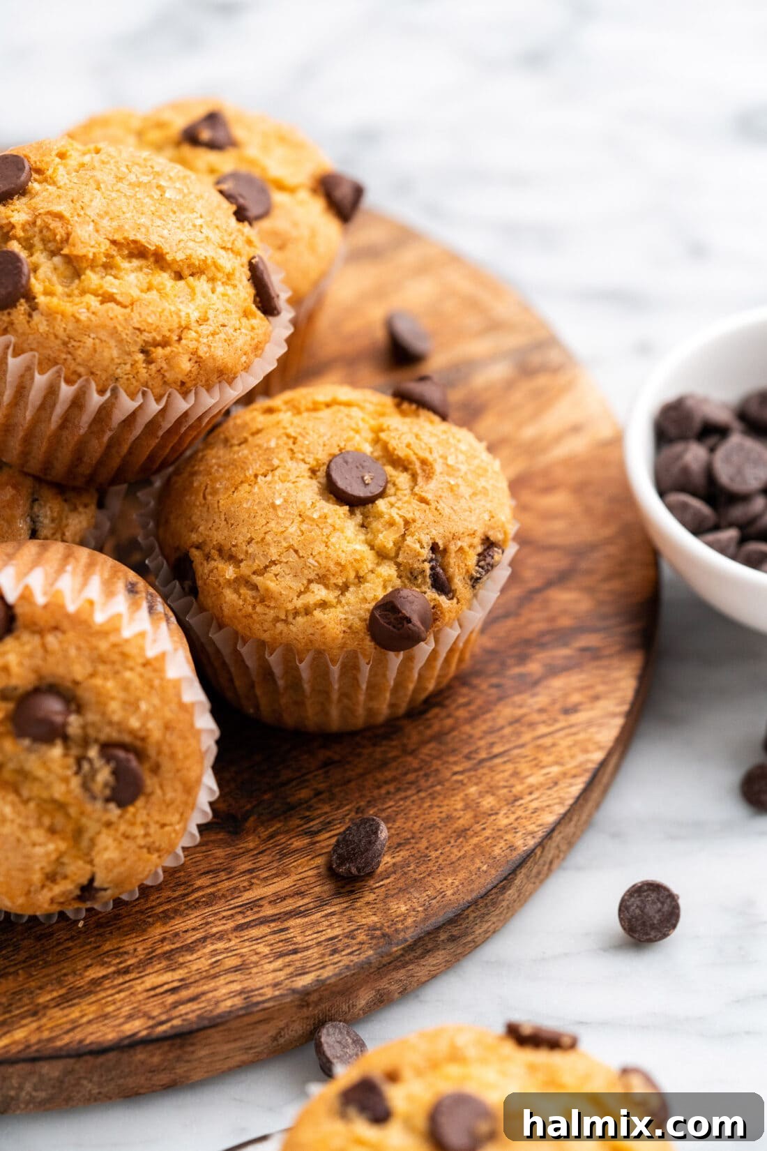 Freshly baked Chocolate Chip Muffins on a rustic wooden platter, showcasing their golden tops and visible chocolate chips