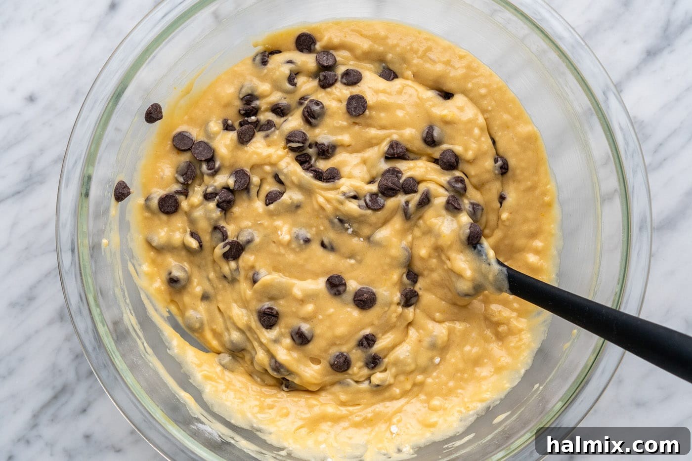 Mixing chocolate chips into the muffin batter with a rubber spatula