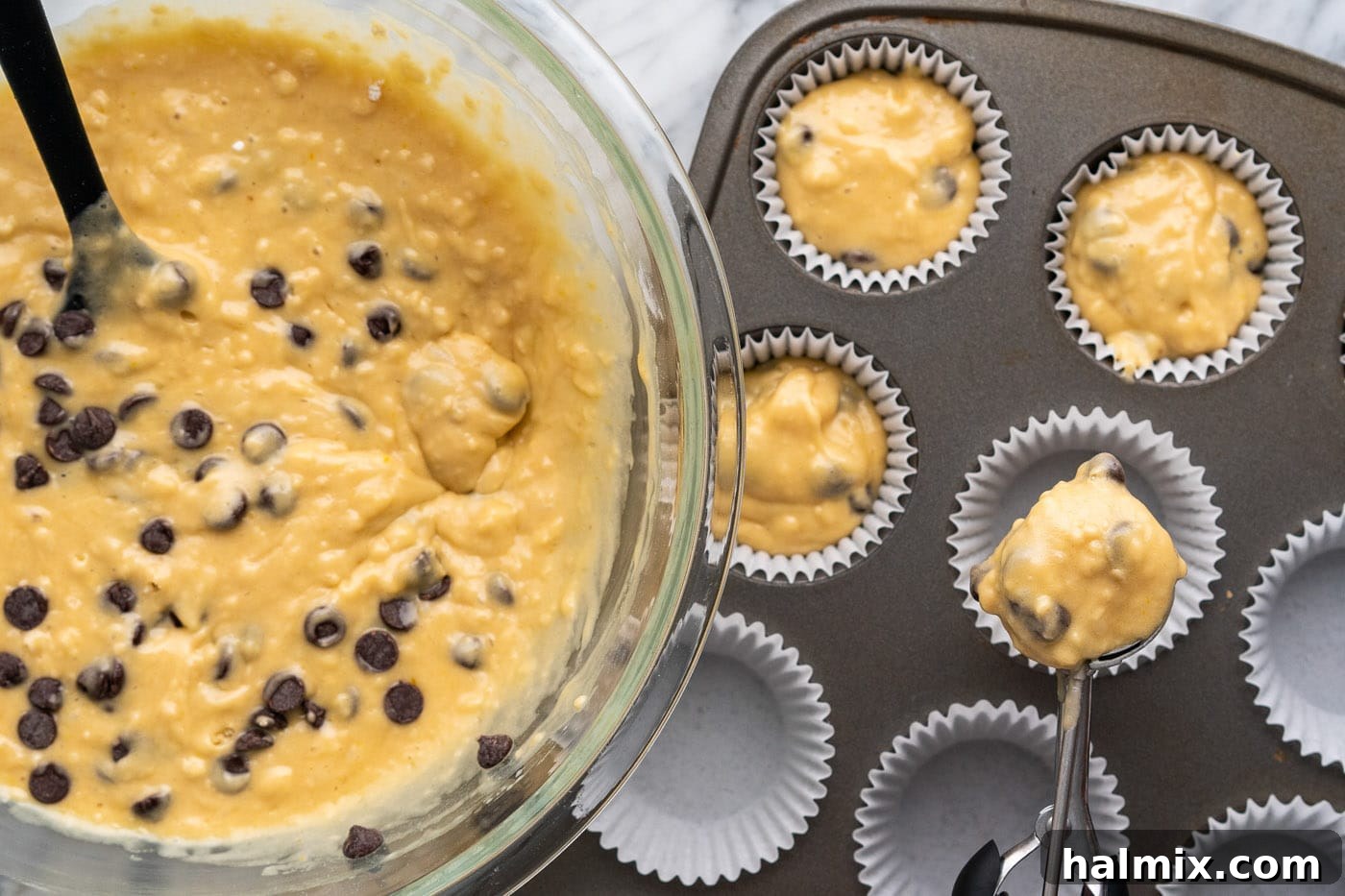 Adding muffin batter to paper-lined muffin pans
