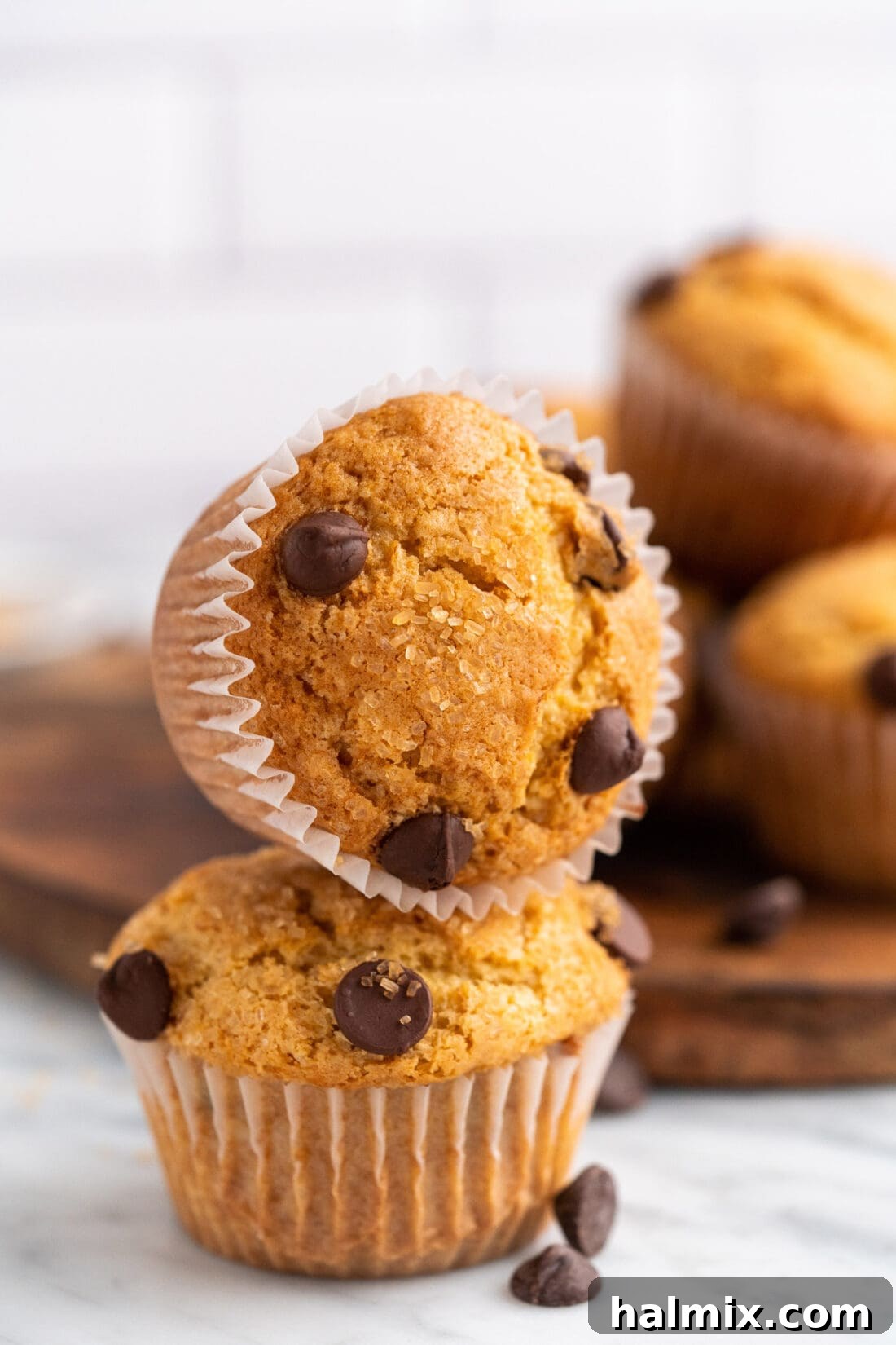 A close-up stack of warm, soft Chocolate Chip Muffins, highlighting their fluffy texture and melted chocolate